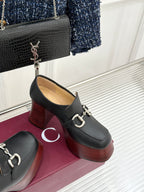 Black leather platform loafers with chunky heel and silver chain hardware detail