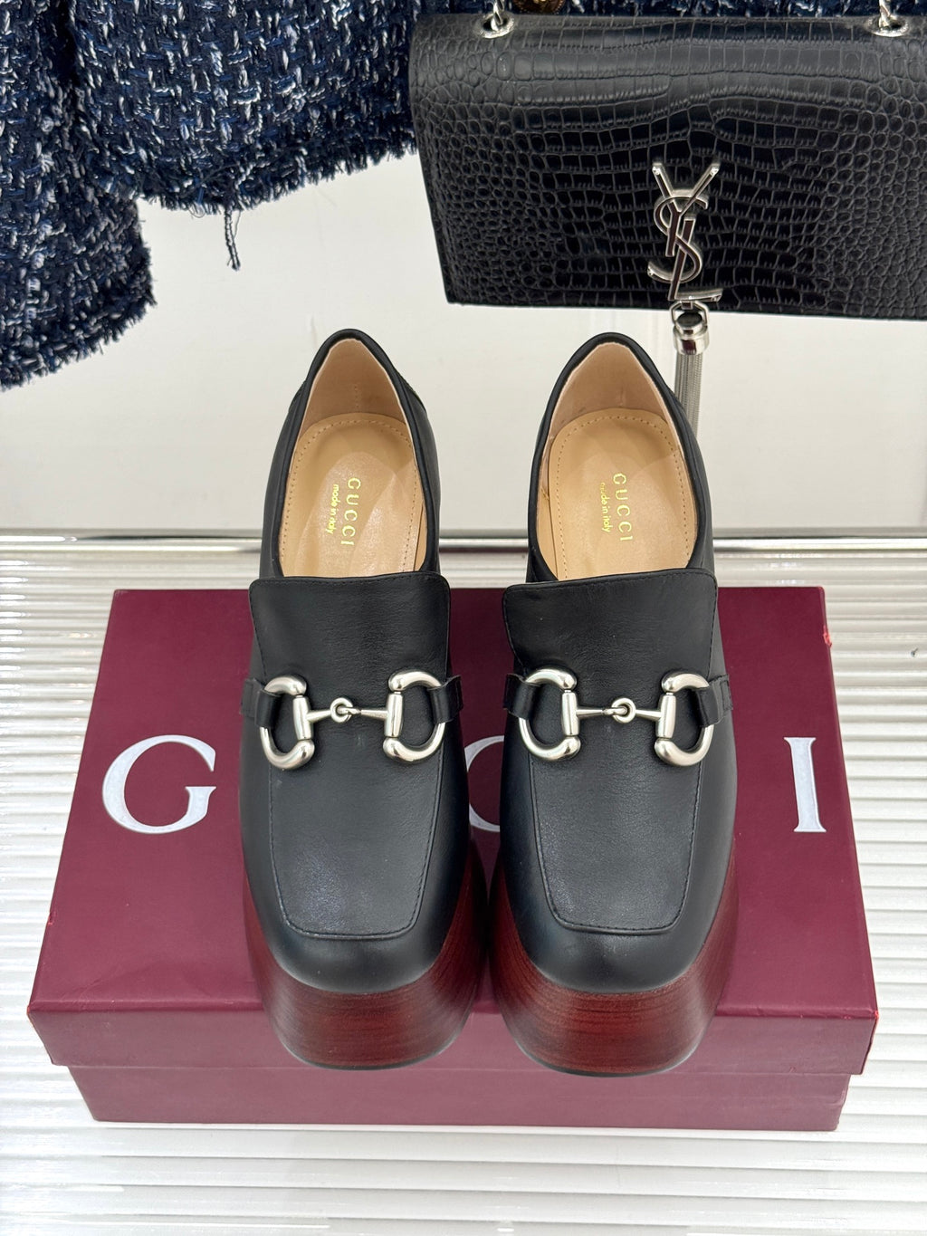 Black leather loafers with silver chain hardware and dark block heel platform