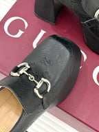 Black Gucci loafer platform heel close-up with gold-tone bit strap hardware