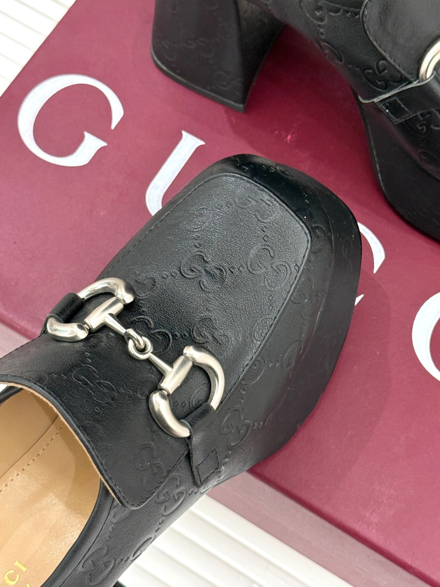 Black Gucci loafer platform heel close-up with gold-tone bit strap hardware