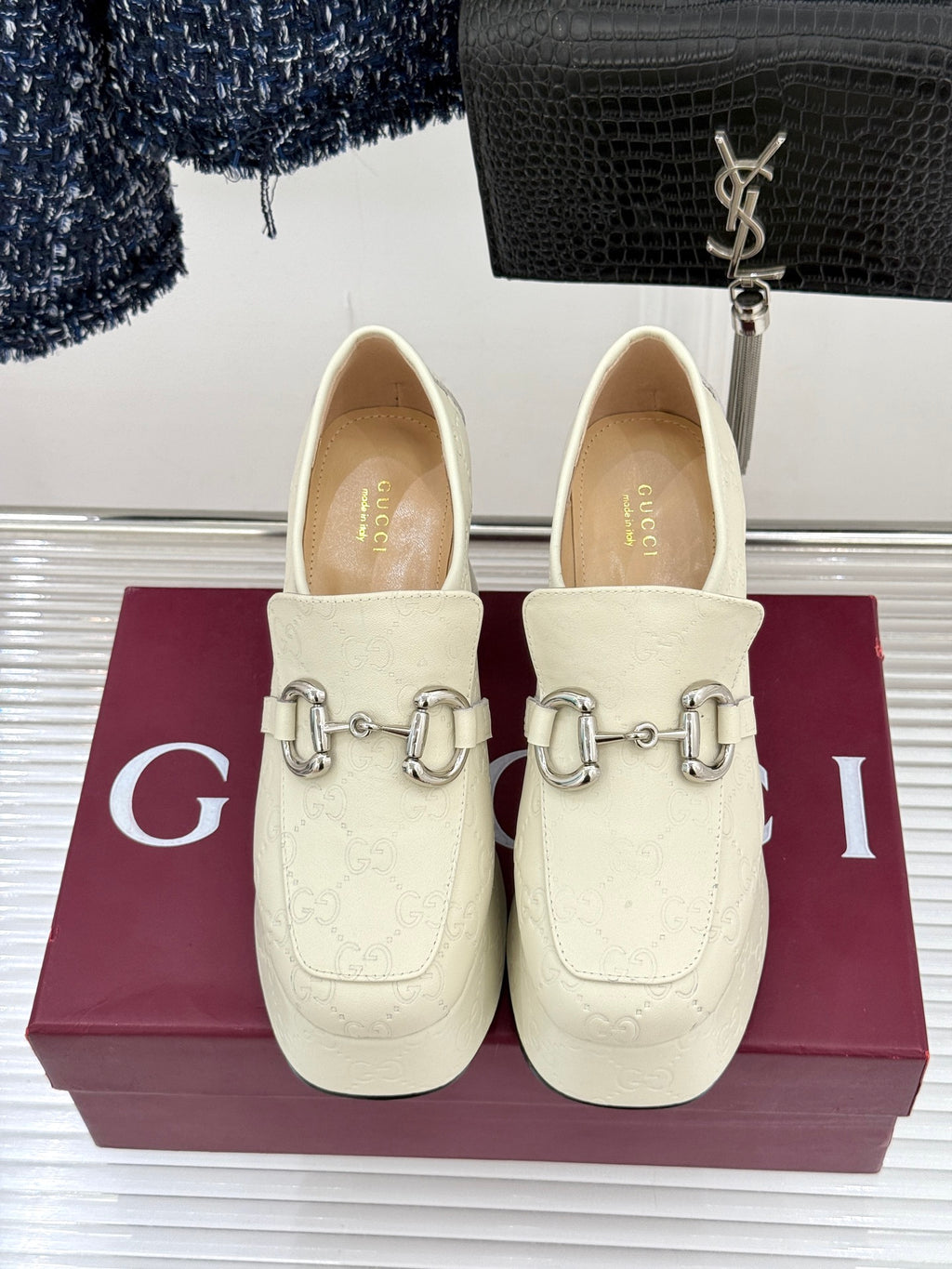 Cream leather loafers with silver horsebit detail, front view on display box