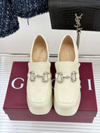 Cream leather loafers with silver horsebit detail, front view on display box