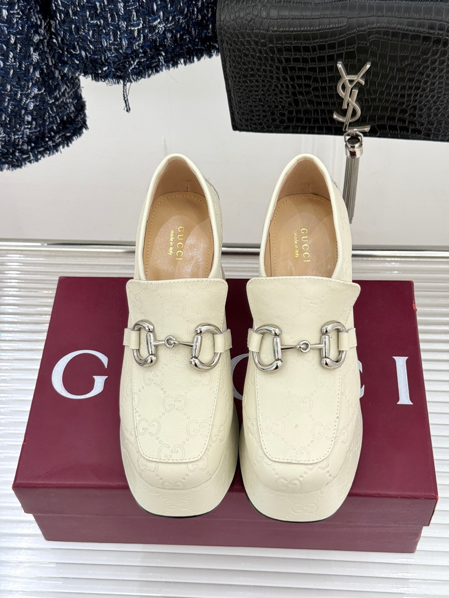 Cream leather loafers with silver horsebit detail, front view on display box