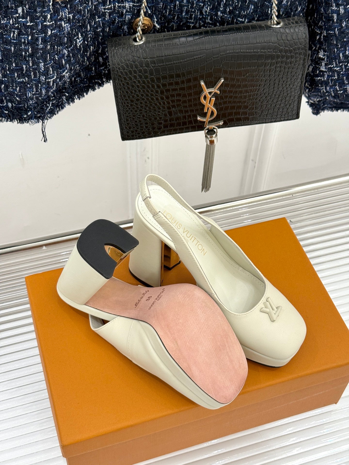 White Louis Vuitton leather pumps with block heels and V logo, on display