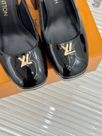 Close-up of black patent leather pumps with LV logo on front
