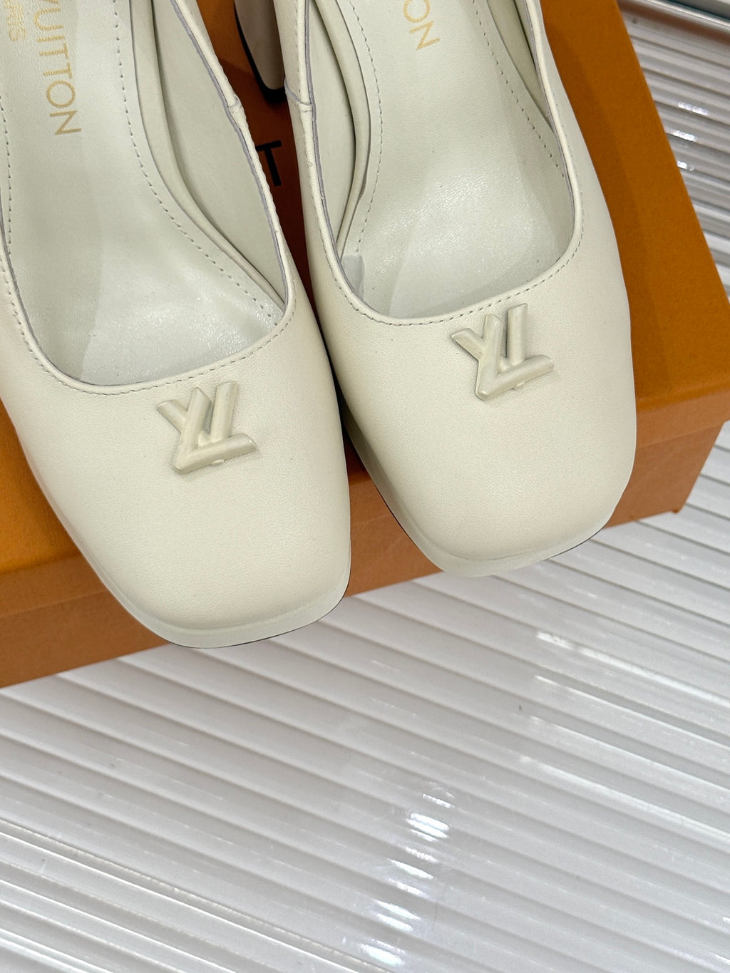 Louis Vuitton cream leather high-heel pumps close-up, LV logo on rounded toe