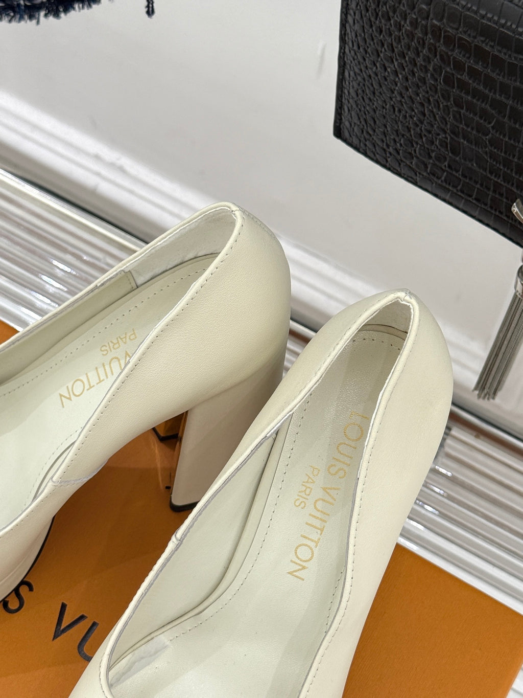 Louis Vuitton cream leather high-heel pumps with LV logo, angled view of both shoes