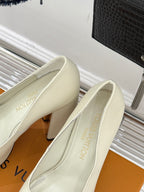 Louis Vuitton cream leather high-heel pumps with LV logo, angled view of both shoes