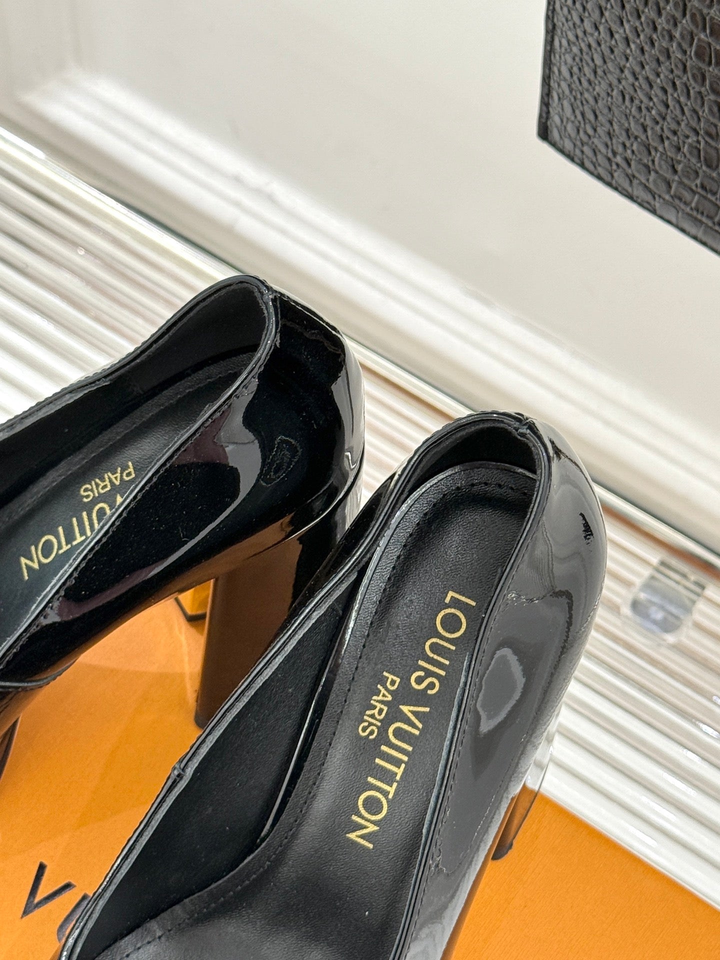 Louis Vuitton black patent pumps with 'Louis Vuitton' on insole, side angle