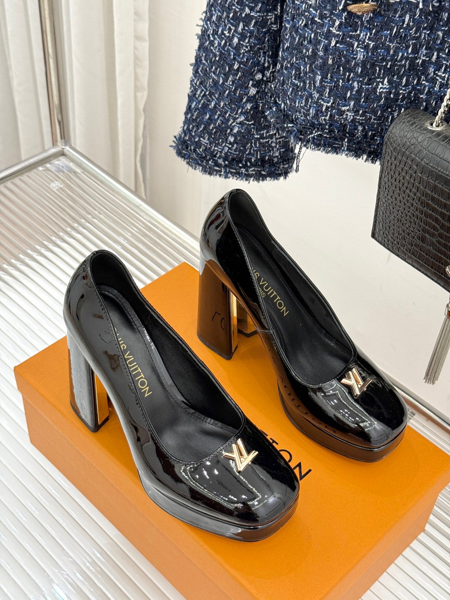 Louis Vuitton black patent high-heel pumps with gold LV emblems, side view
