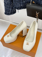 Pair of white leather pumps with pointed toe, chunky heel, and gold logo hardware