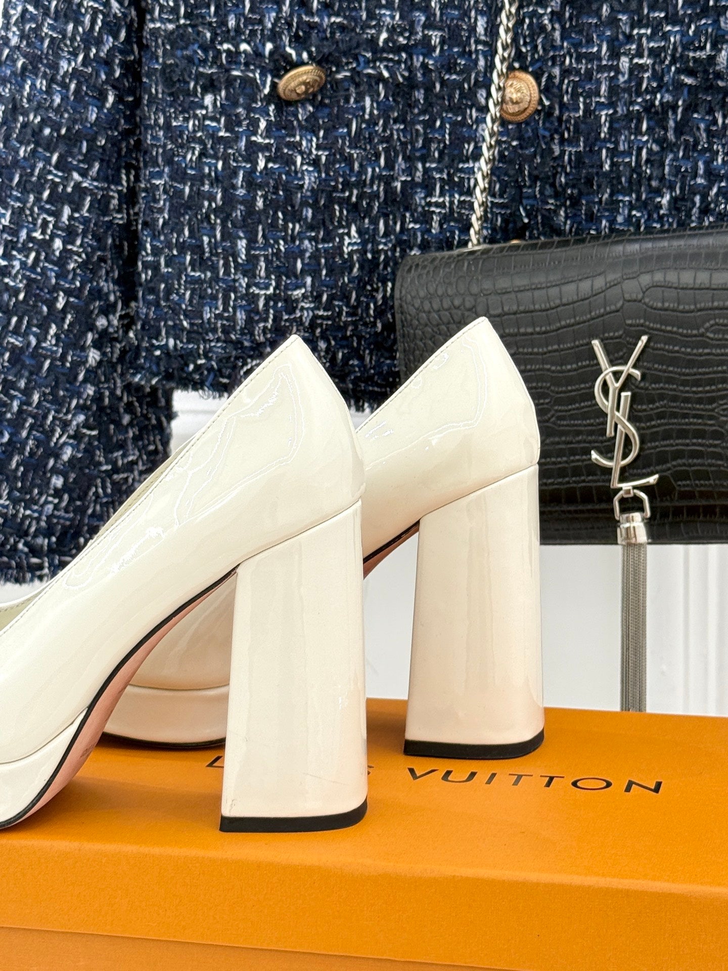 White leather heeled pumps with chunky block heels and gold logo detail at the toe