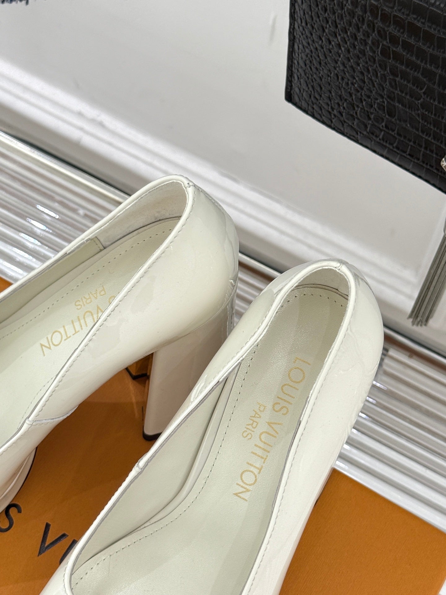 White leather pumps with pointed toe and gold logo accent, shown from side angle