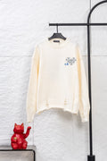 Cream long-sleeve knit sweater with blue and gray graphic embroidery on chest