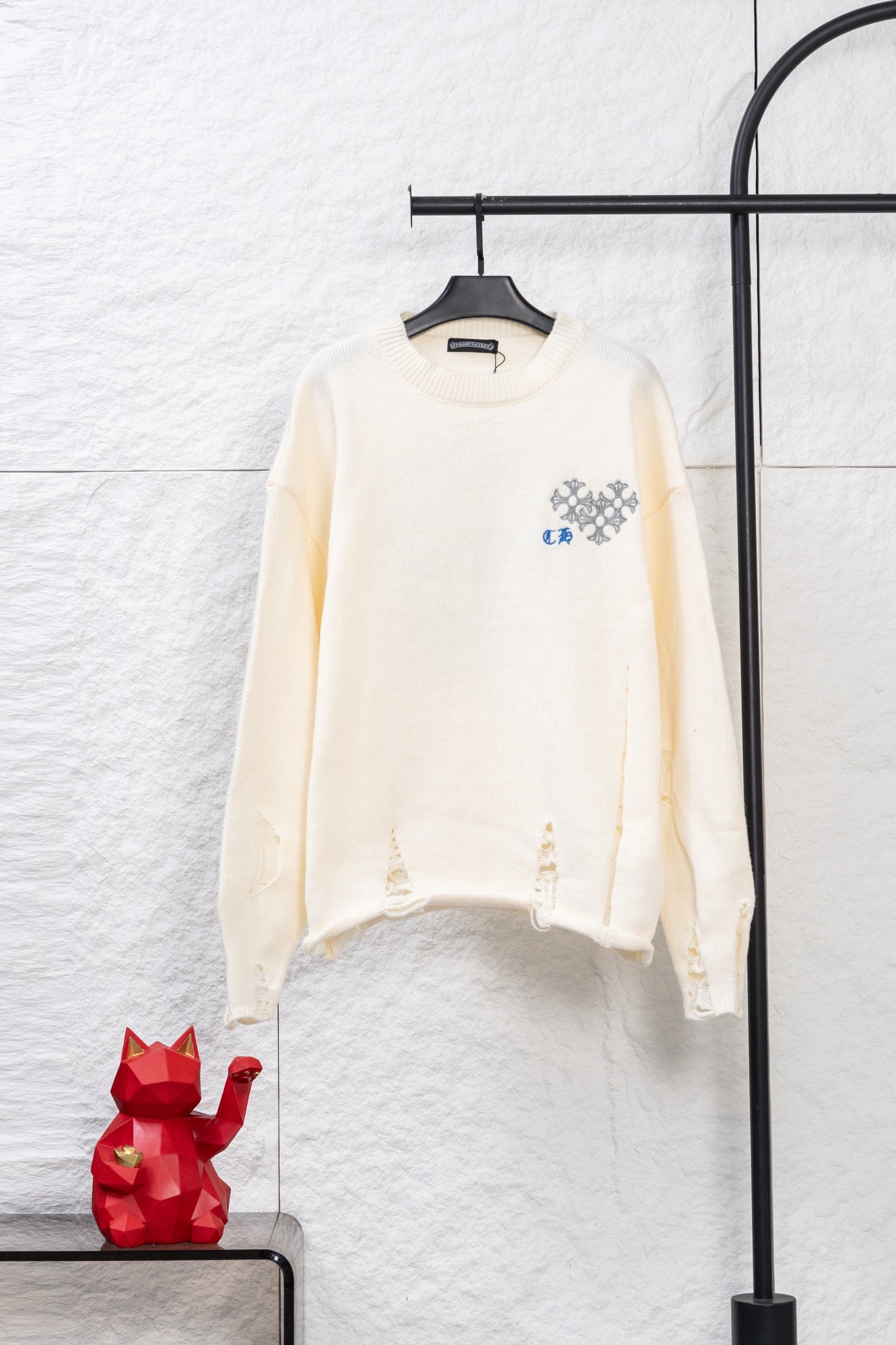 Cream long-sleeve knit sweater with blue and gray graphic embroidery on chest