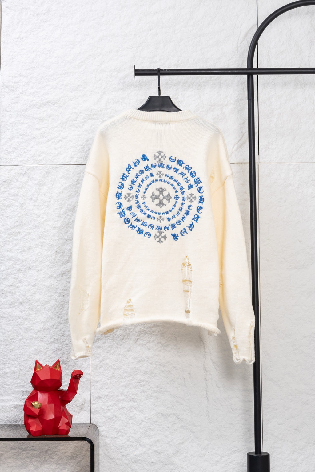Cream long-sleeve knit sweater with large blue circular embroidery and sleeve details
