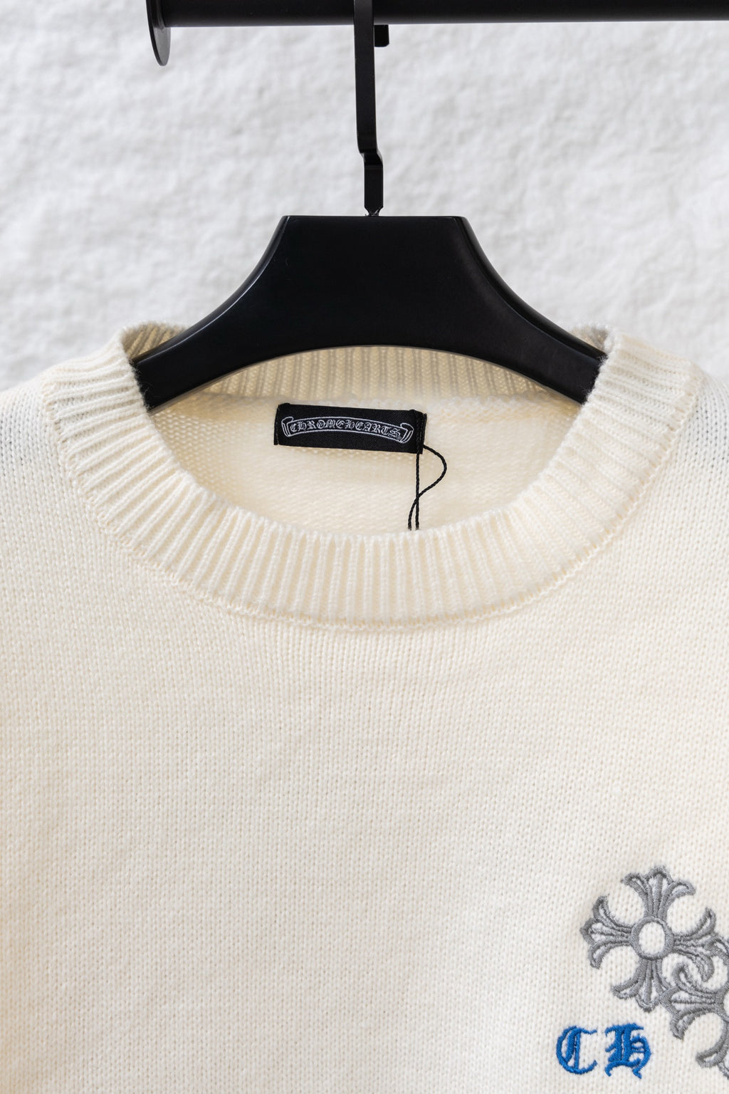 Cream knit sweater neckline with blue-gray floral embroidery on chest
