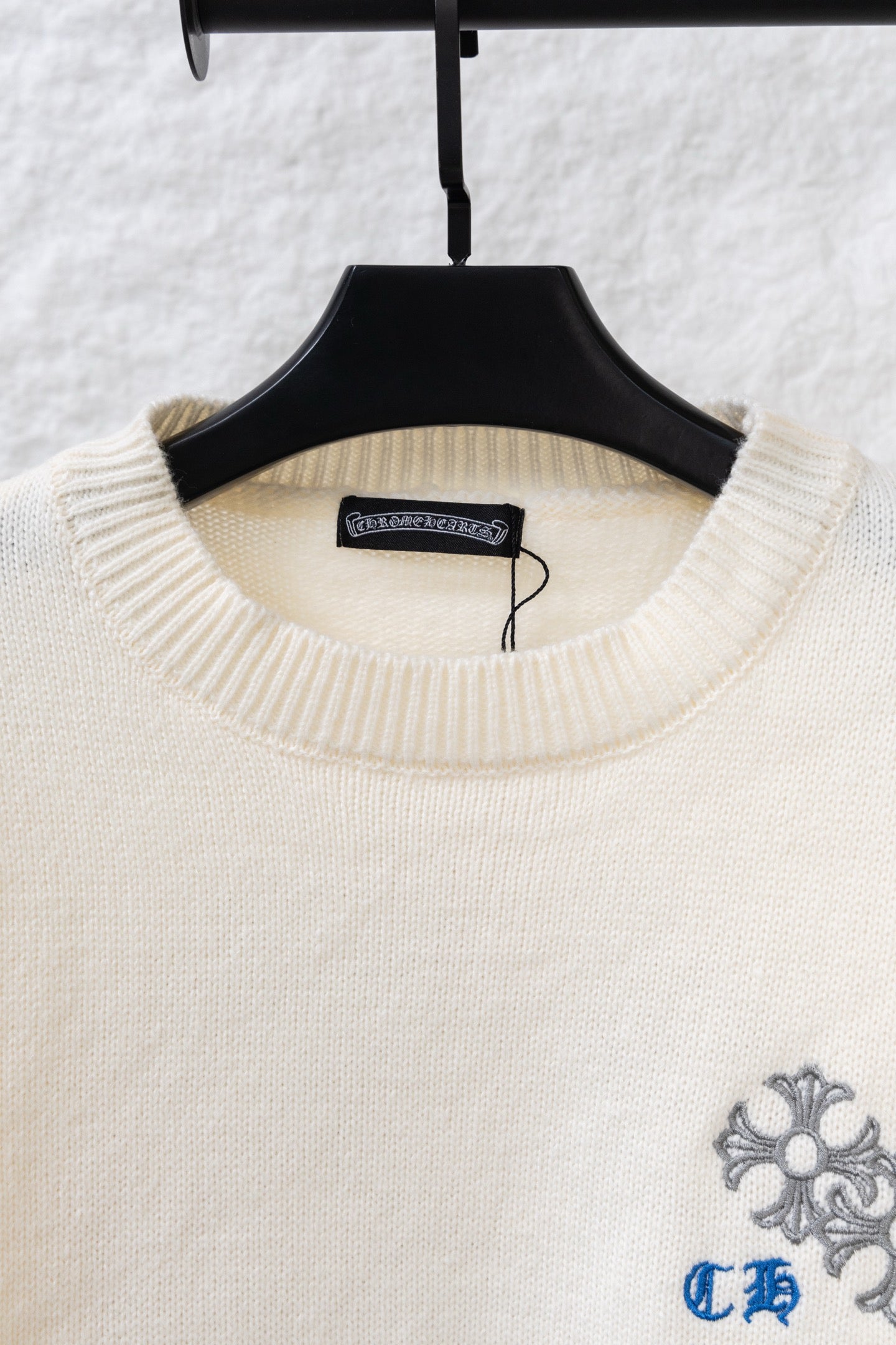 Cream knit sweater neckline with blue-gray floral embroidery on chest