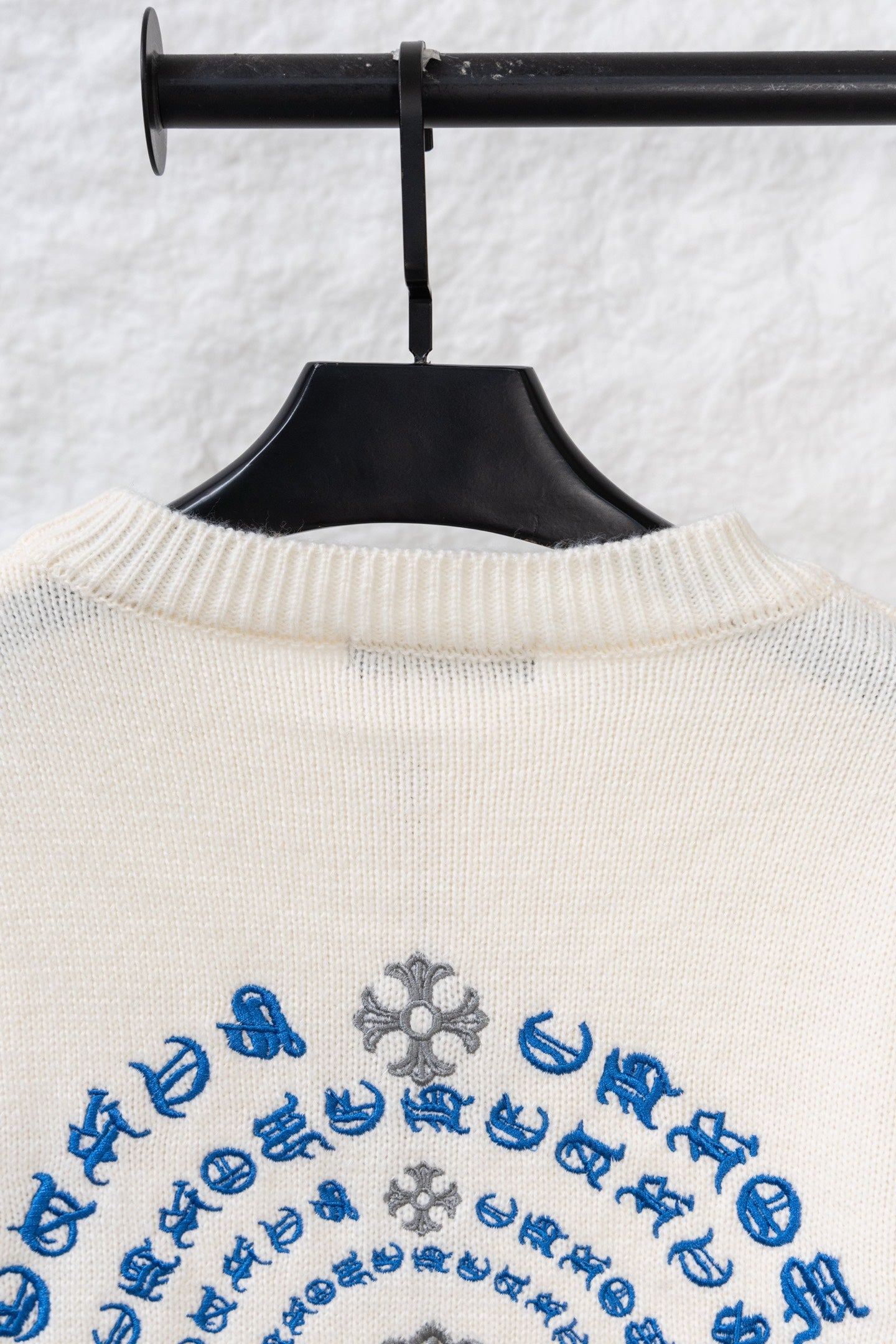 Cream knit long sweater with ribbed collar and blue patterned embroidery