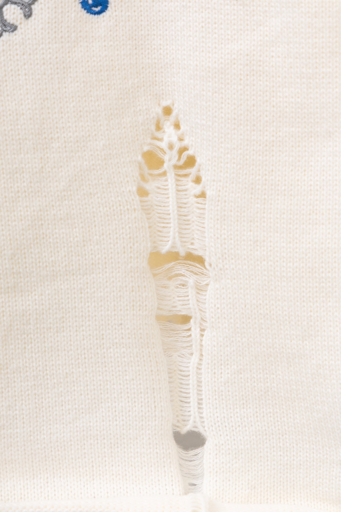 Close-up of cream threaded vertical embroidery on a knit sweater