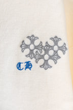 Close-up of gray flower embroidery and blue accent on a cream knit sweater