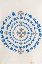 Close-up of blue and gray circular embroidery on a cream knit sweater