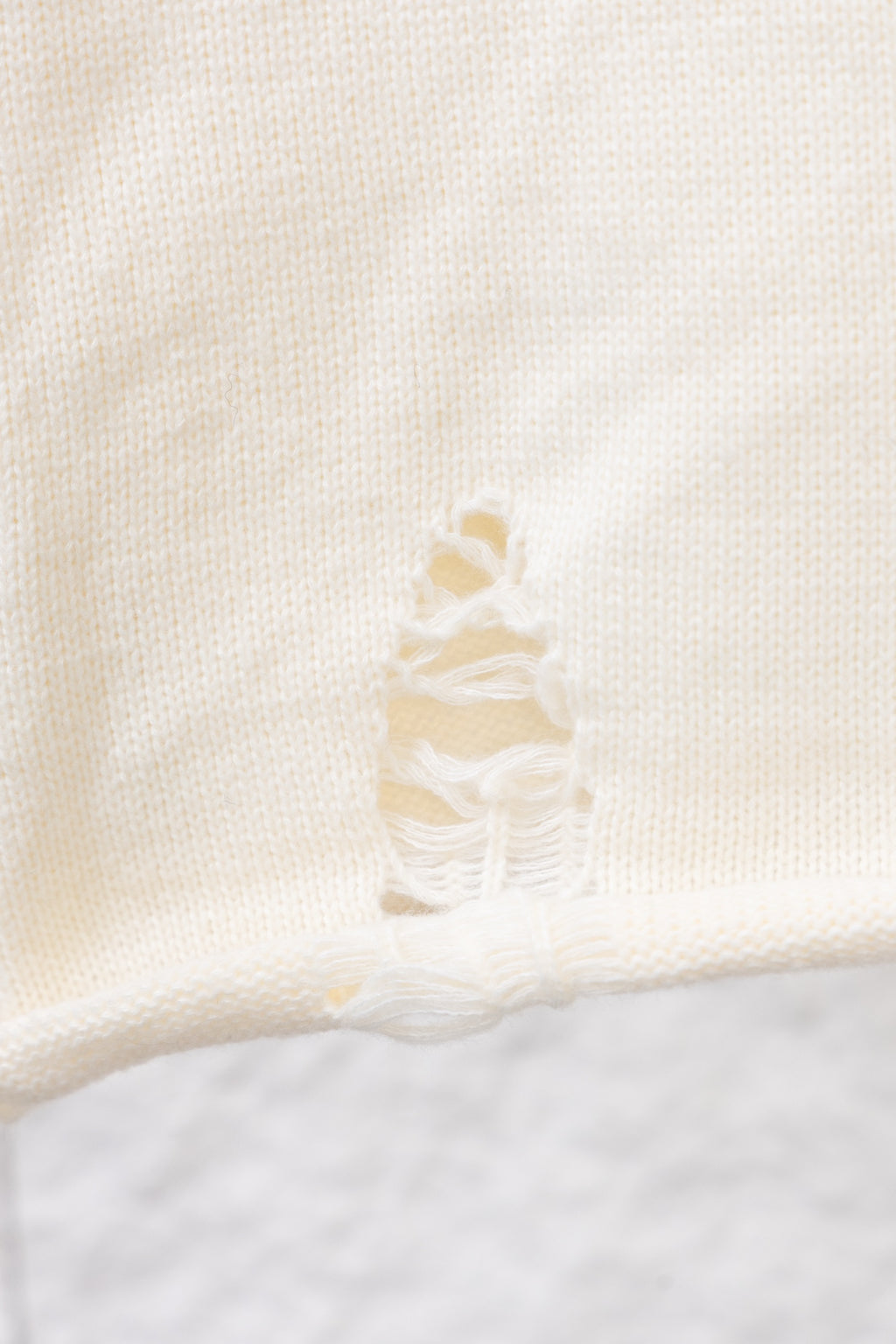 Close-up of cream raised bow-like embroidery on a knit sweater