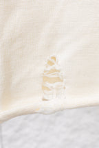 Close-up of cream raised bow-like embroidery on a knit sweater