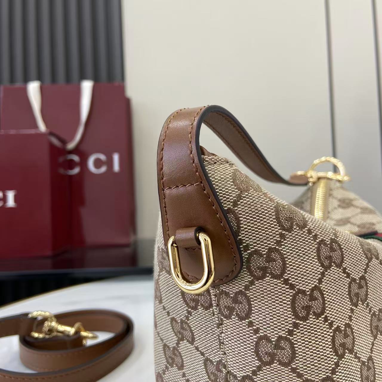Gucci monogram shoulder bag side view with brown leather strap and gold hardware