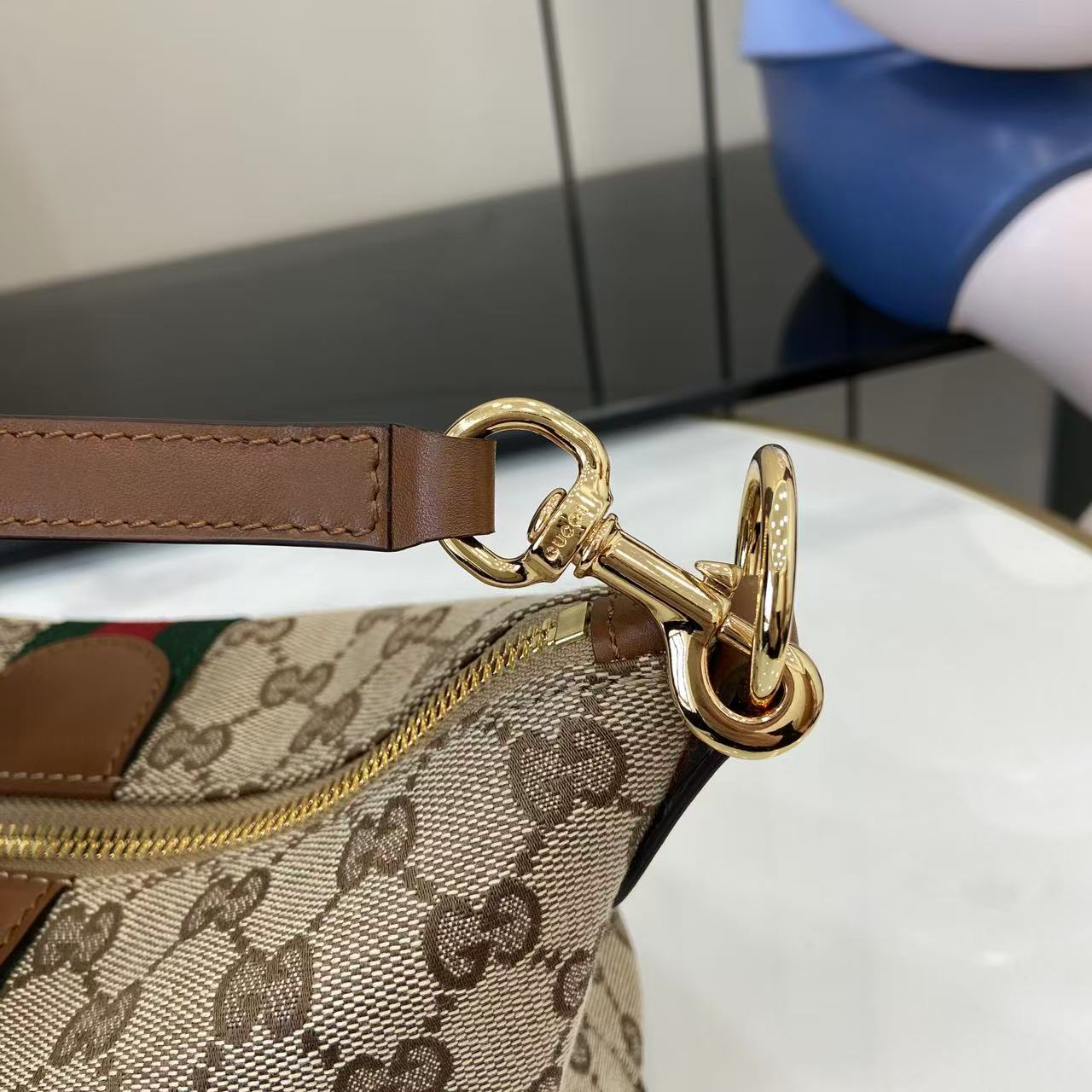 Gucci monogram bag hardware close-up with gold clasp and brown leather strap
