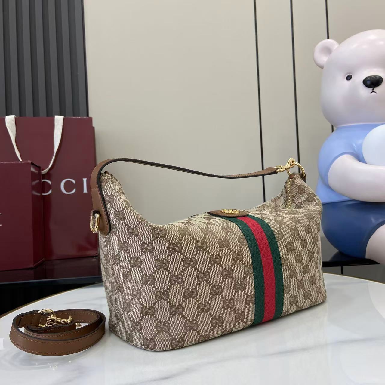 Gucci hobo bag on side view with GG canvas, green/red web stripe and shoulder strap