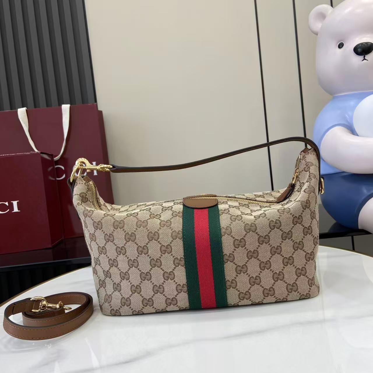 Gucci hobo bag front view with GG canvas, green and red web stripe, gold clasp