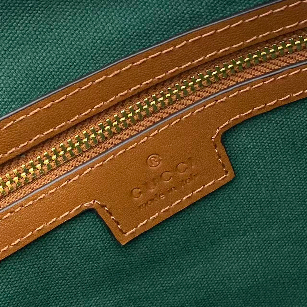 Gucci bag close-up: green interior and brown leather trim with stitched edge and emboss logo