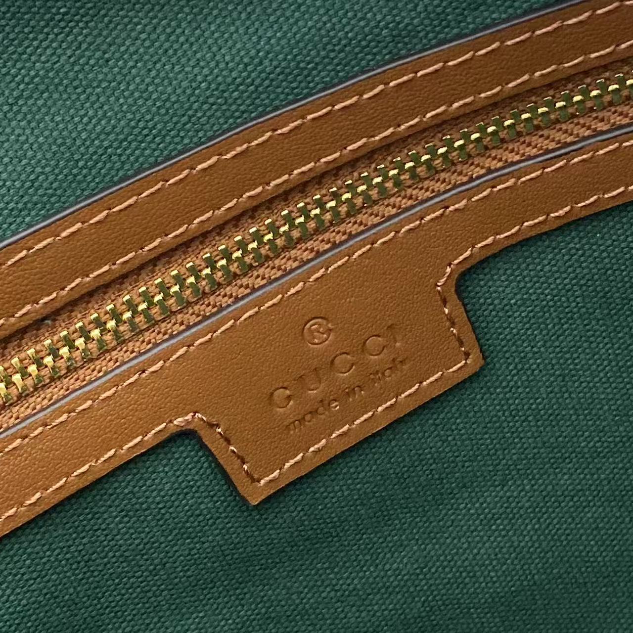 Gucci bag close-up: green interior and brown leather trim with stitched edge and emboss logo
