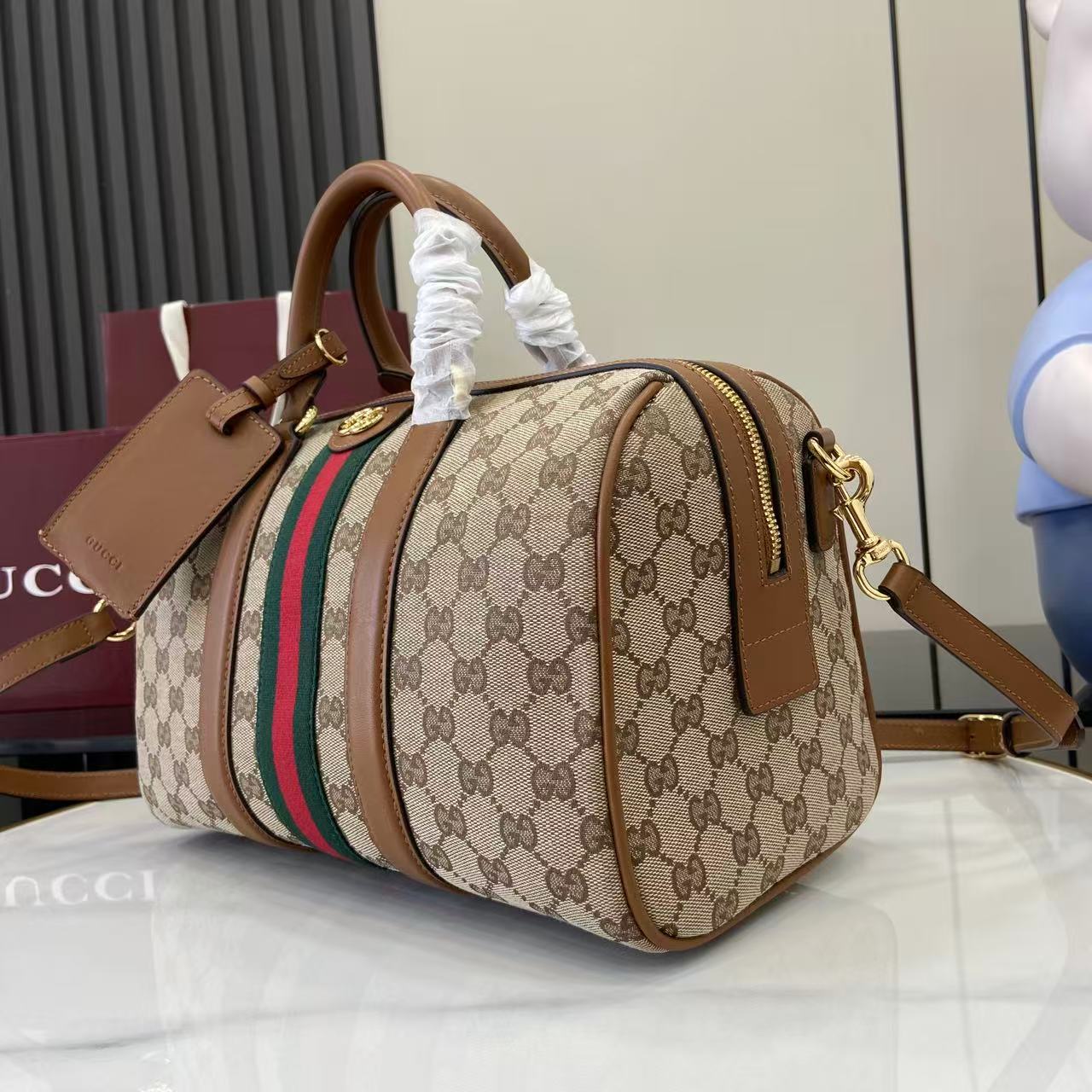 Gucci duffel bag angled view with GG canvas, multicolor web stripe, gold-tone zipper pull