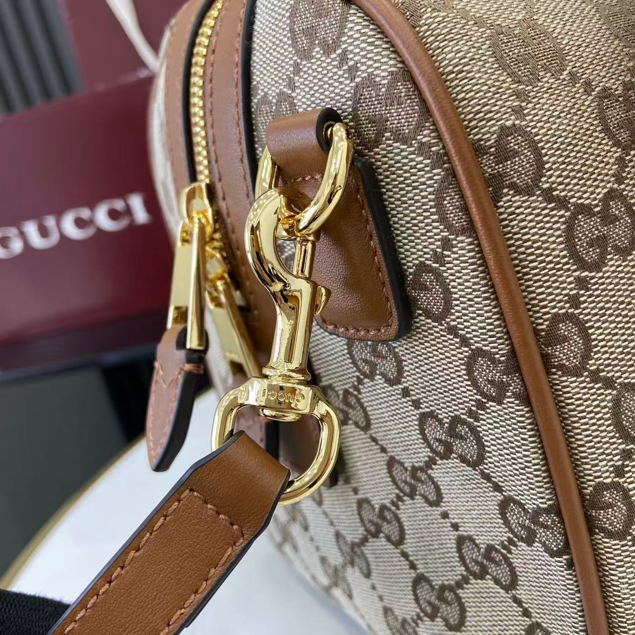 Gucci bag with GG monogram canvas, brown leather trim, and gold clasp hardware