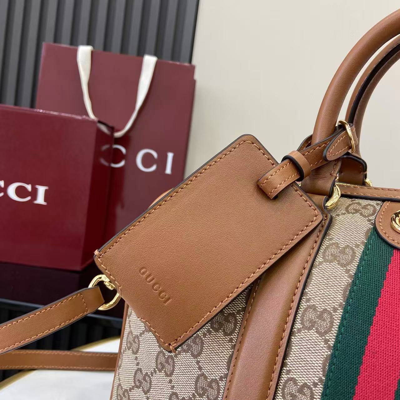 Gucci bag close-up of front pocket with brown leather flap, GG canvas, and web stripe