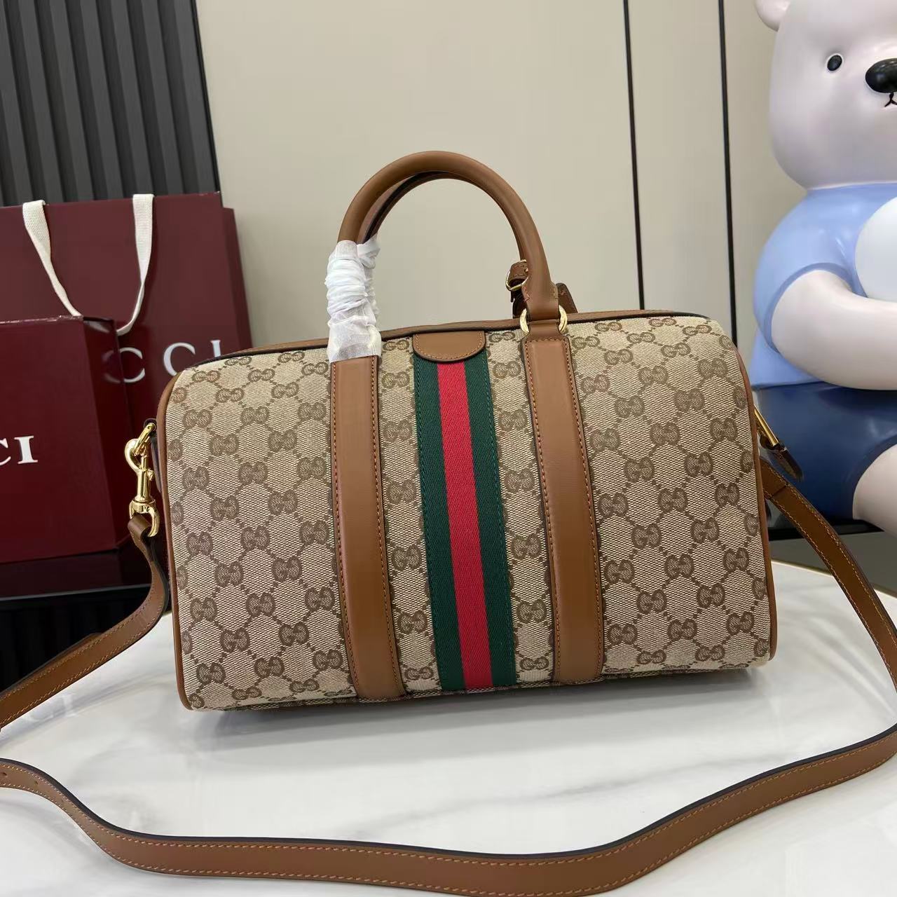 Gucci duffel bag front view in GG canvas with multicolor web stripe and brown crossbody strap