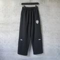 Black wide-leg pants with elastic waistband and small crest logo on left thigh