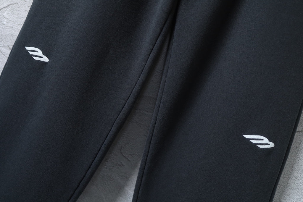 Black wide-leg pants with small white logo marks near hem