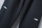 Black wide-leg pants with small white logo marks near hem