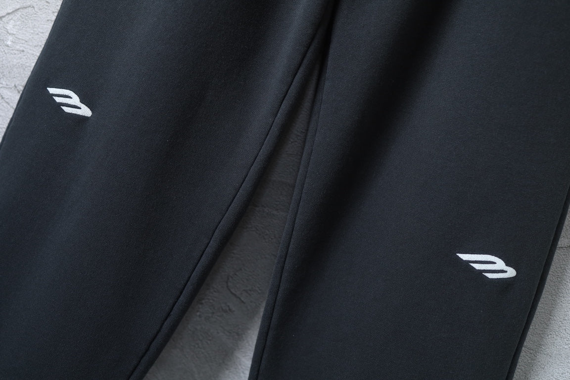 Black wide-leg pants with small white logo marks near hem