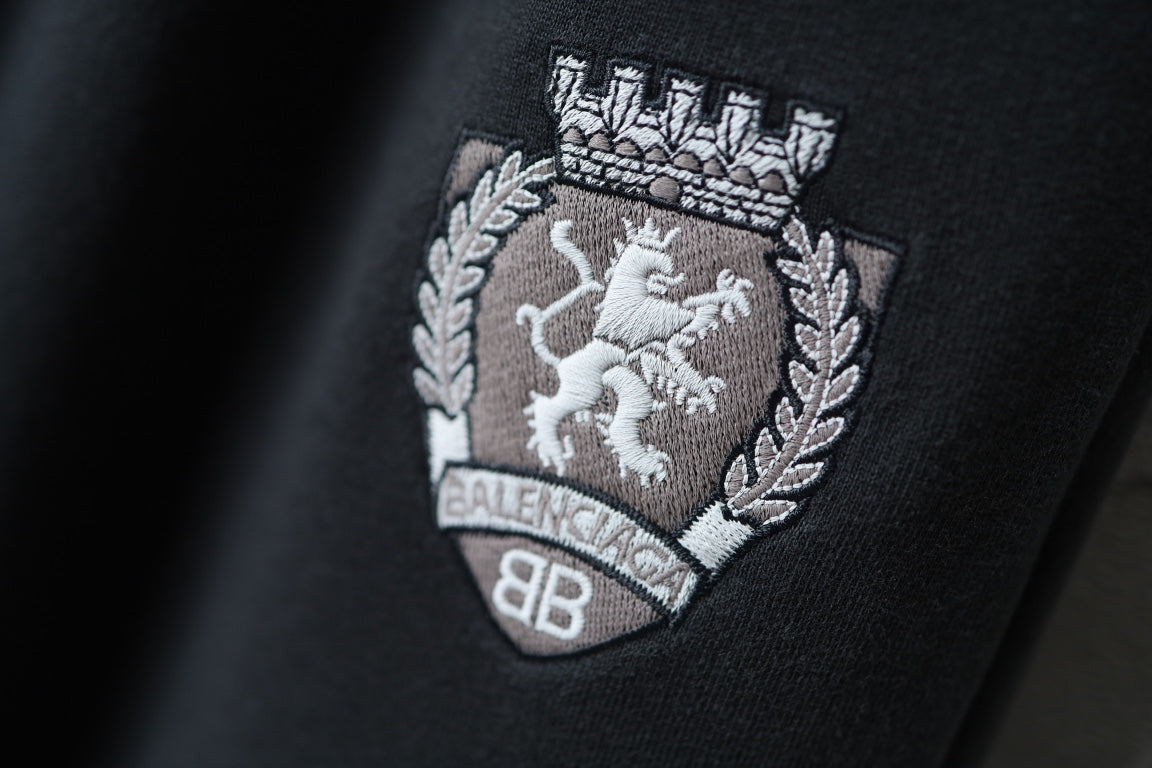 Black pants with embroidered crest patch and wreath detail