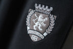 Dark pants with embroidered crest patch logo and laurel detail on the leg