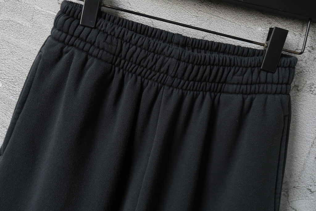 Dark pants with elastic waistband and stitched front pleats, side view