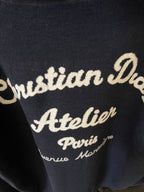 Dior long hoodie close-up of “Atelier” script embroidery on navy knit