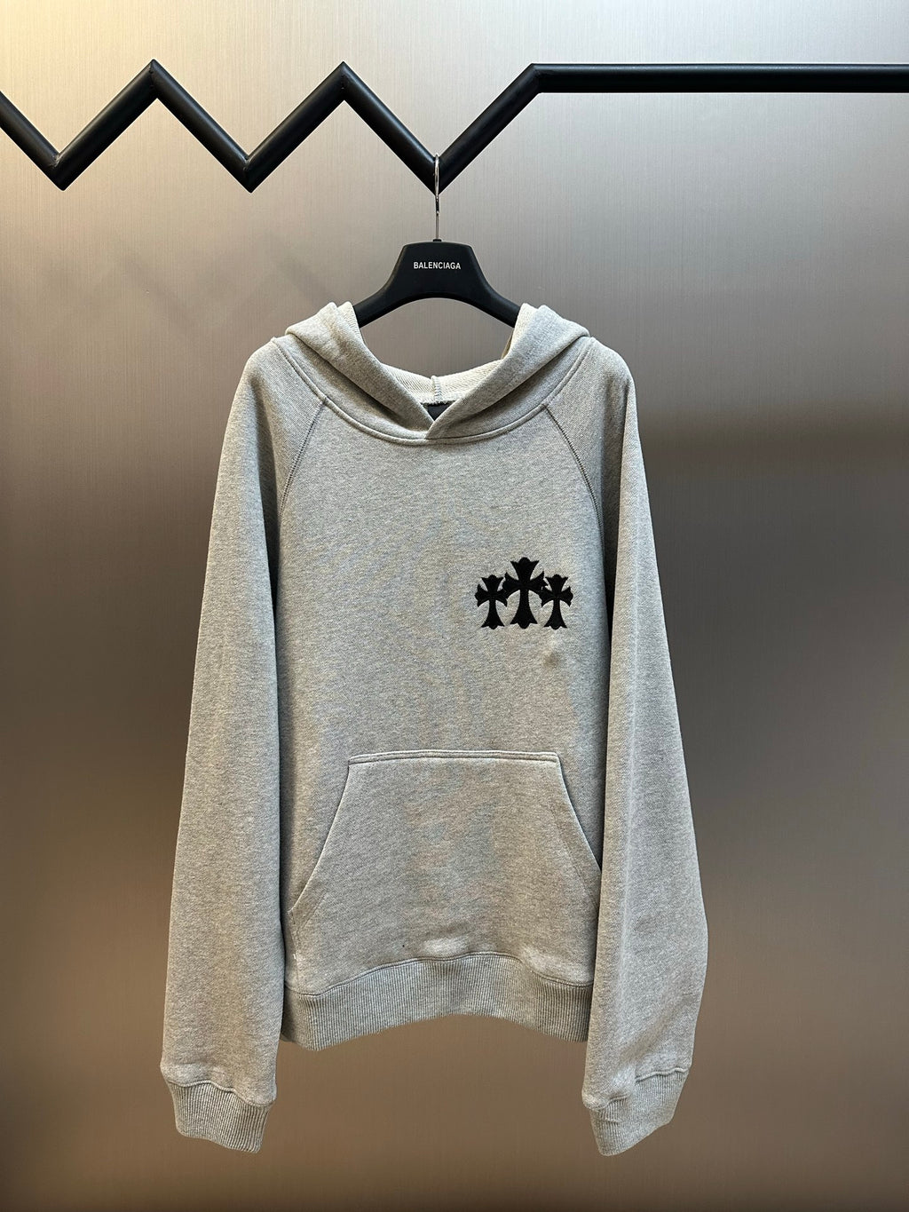 Light gray hooded sweatshirt with black cross logo on chest and front pocket