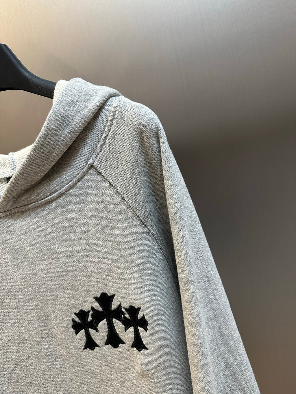 Light gray hooded sweatshirt sleeve with black logo embroidery