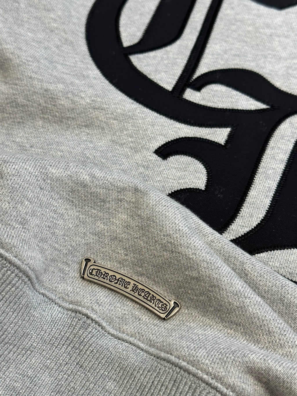 Light gray sweatshirt with black graphic and small leather-look brand patch