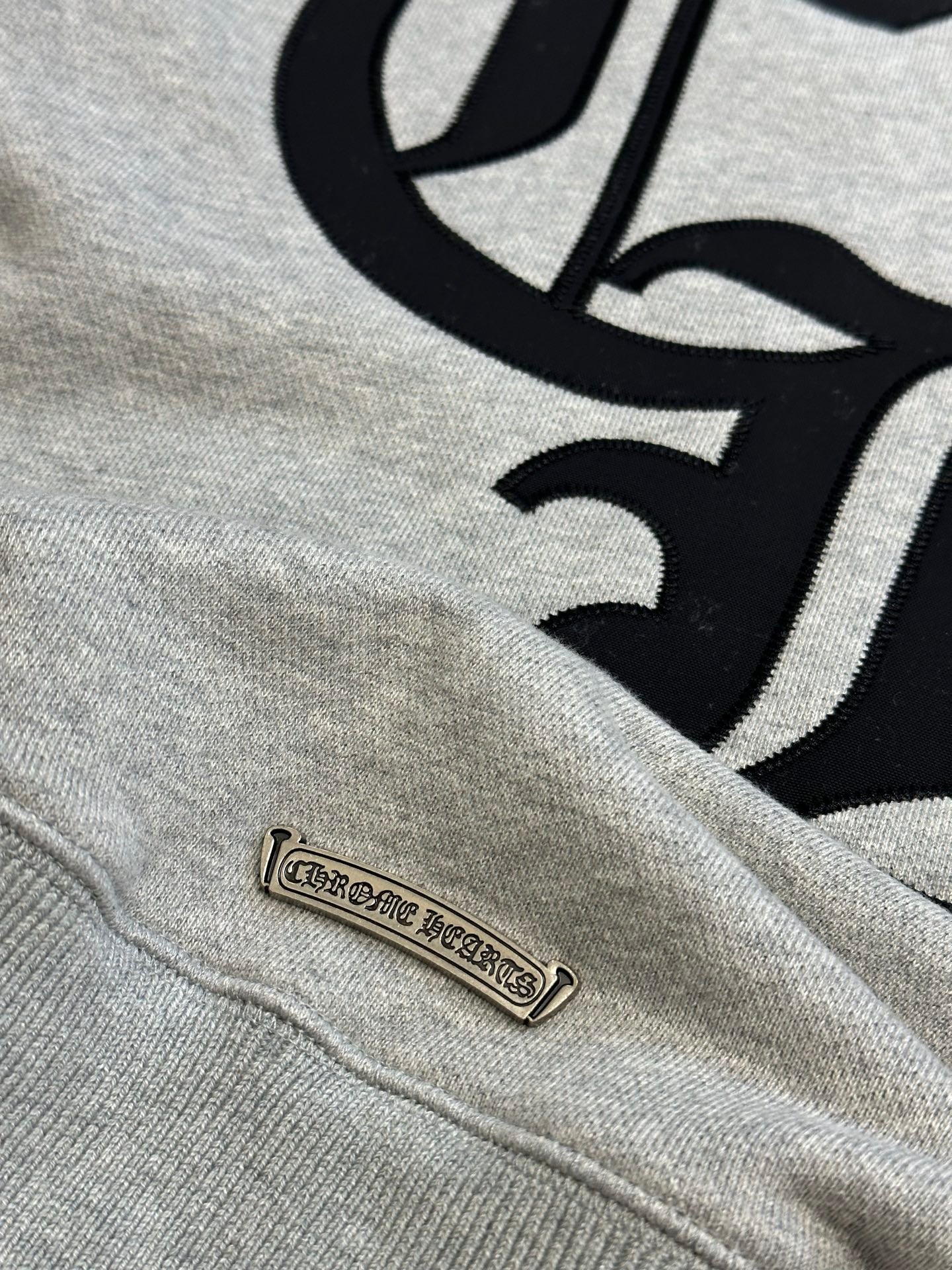 Light gray sweatshirt with black graphic and small leather-look brand patch